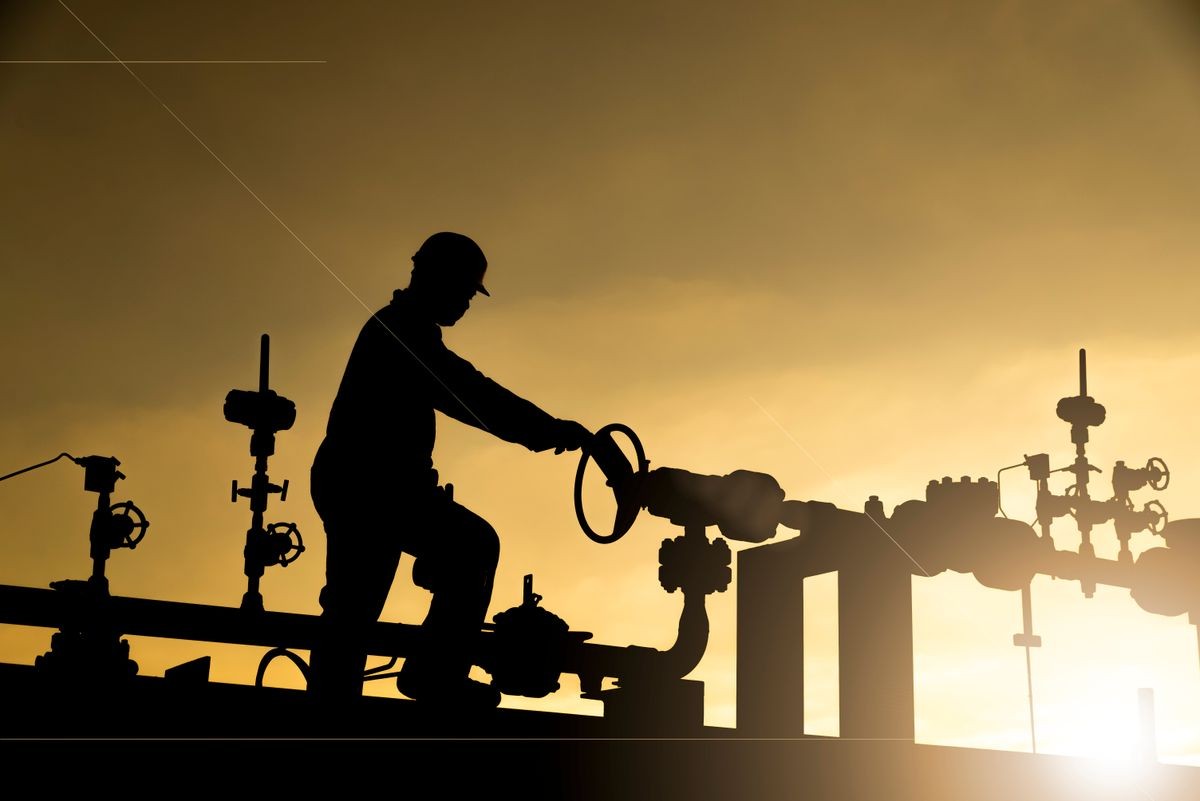 Silhouette of the oilfield worker monitoring the manifold valves in the oilfield 